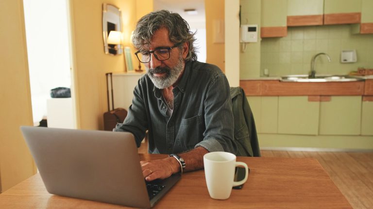 Man writing at kitchen table — be a HyperLocal Loop contributor